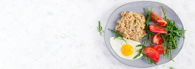 Kahvaltı yulaf lapası, sahanda yumurta, domates ve roka. Sağlıklı yiyecekler. Üst görünüm, genel görünüm, afiş