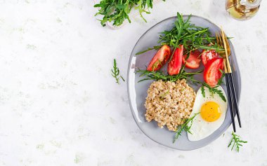 Kahvaltı yulaf lapası, sahanda yumurta, domates ve roka. Sağlıklı yiyecekler. Üst görünüm, genel görünüm, kopyalama alanı