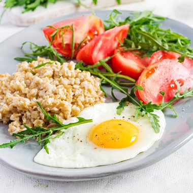 Kahvaltı yulaf lapası, sahanda yumurta, domates ve roka. Sağlıklı yemek..