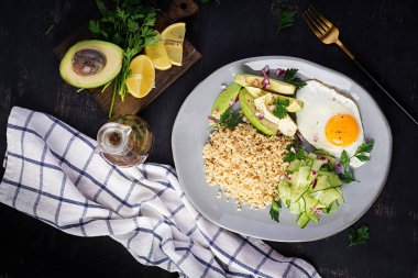 Diyet menüsü. Sağlıklı bir yaşam tarzı. Bulgur lapası, kızarmış yumurta ve taze sebzeler. Tabakta salatalık ve avokado. Üst görünüm, genel görünüm, kopyalama alanı