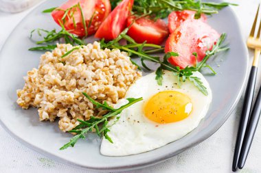 Kahvaltı yulaf lapası, sahanda yumurta, domates ve roka. Sağlıklı yemek..