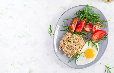 Kahvaltı yulaf lapası, sahanda yumurta, domates ve roka. Sağlıklı yiyecekler. Üst görünüm, genel görünüm, kopyalama alanı