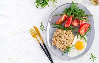 Kahvaltı yulaf lapası, sahanda yumurta, domates ve roka. Sağlıklı yiyecekler. Üst görünüm, genel görünüm, kopyalama alanı