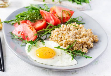 Kahvaltı yulaf lapası, sahanda yumurta, domates ve roka. Sağlıklı yemek..