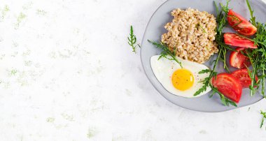 Kahvaltı yulaf lapası, sahanda yumurta, domates ve roka. Sağlıklı yiyecekler. Üst görünüm, genel görünüm, kopyalama alanı