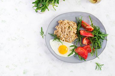 Kahvaltı yulaf lapası, sahanda yumurta, domates ve roka. Sağlıklı yiyecekler. Üst görünüm, genel görünüm, kopyalama alanı
