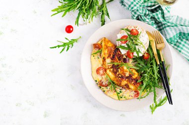 Domatesli omlet, peynir ve tabakta yeşil otlar. Frittata - İtalyan omleti. Üst görünüm, genel görünüm, kopyalama alanı