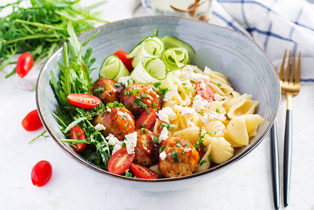 Italian pasta. Conchiglie with meatballs, feta cheese and salad on light background. Dinner. Slow food concept