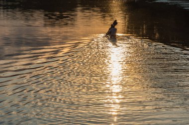 Akşam nehirde iki kişi ile bir tekne yelken