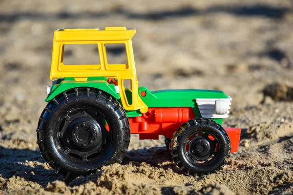 Oyuncak traktör kumun üzerinde duruyor