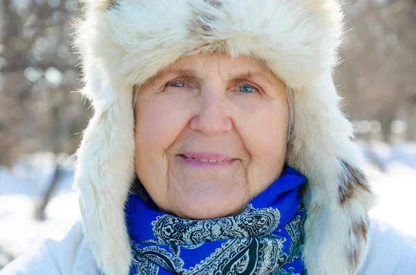 Портрет счастливой, улыбающейся бабушки. смотреть в камеру. Кавказка старшеклассница холодной зимой. Девушка из моды снаружи. Бабушка с голубыми глазами в меховой шляпе. веселые, веселые старики наслаждаются снегом — стоковое фото
