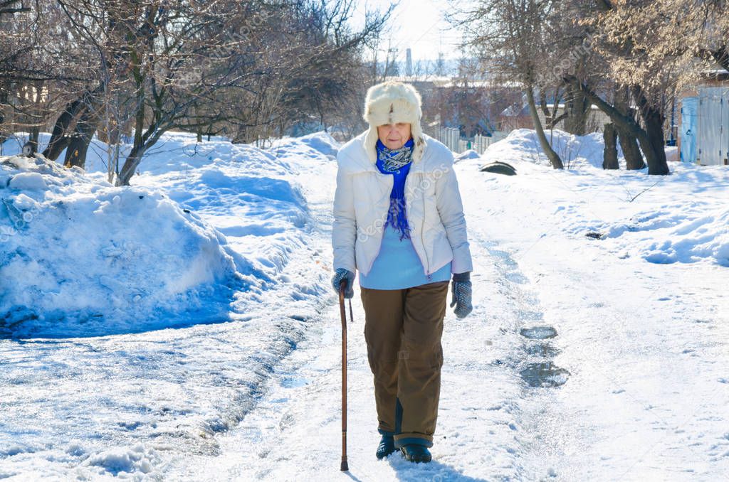 grandmother walk with cane on road. old person leaning on a walking stick. caucasian female senior at cold winter. fashion lady outside. healthy leisure of grandma in fur hat. .