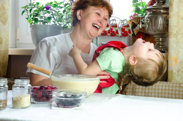 Ritratto di volti, mani felice nonna abbraccio nipote. bambina giocare con la nonna in cucina. bambino bambino tenere la nonna e ridere. Famiglia accogliente Guardarsi l'un l'altro — Foto Stock