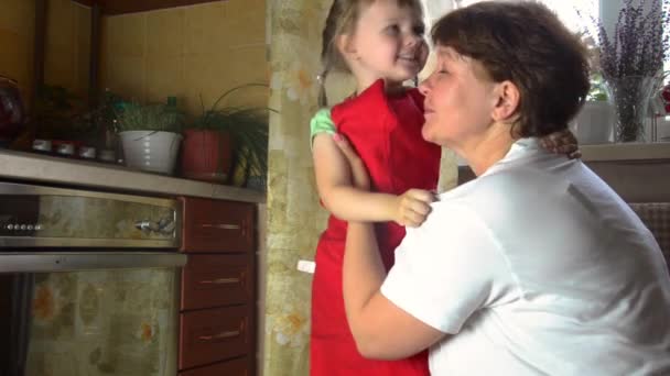 Porträt von Gesichtern, glückliche Hände Oma umarmen Enkelin. Kleinkind Mädchen spielen mit Großmutter auf Küche. Baby hält Oma und lacht. Gemütlicher Familienanblick