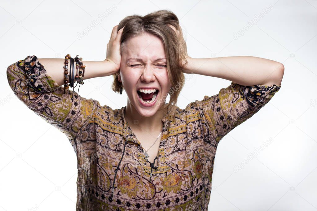 Emotions is stress, madness. concept crazy shouting. woman rending her hair. natural teenager screaming with close eyes and wide open mouth, holding hands on head. Sad blond girl
