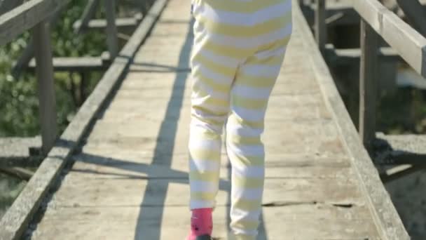 Pequeña niña paseando a través de un antiguo puente — Vídeos de Stock