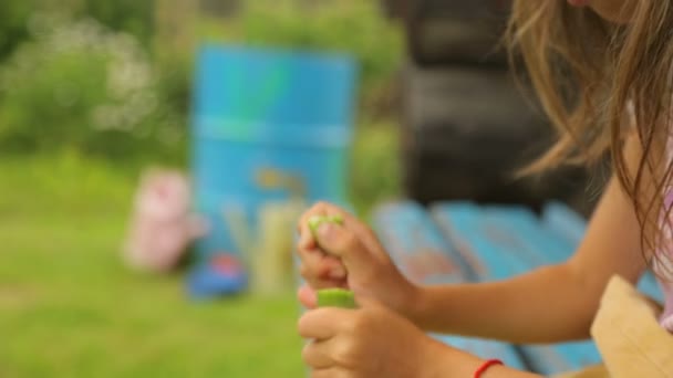 Kleines Mädchen isst Bohnen im Garten
