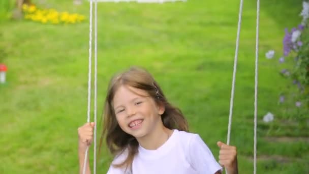 Маленькая девочка, качающаяся в саду — стоковое видео
