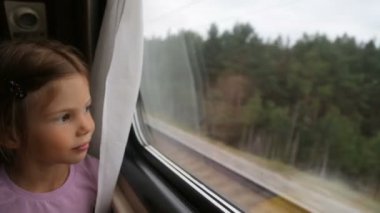 Trendeki pencereden bakan küçük kız.