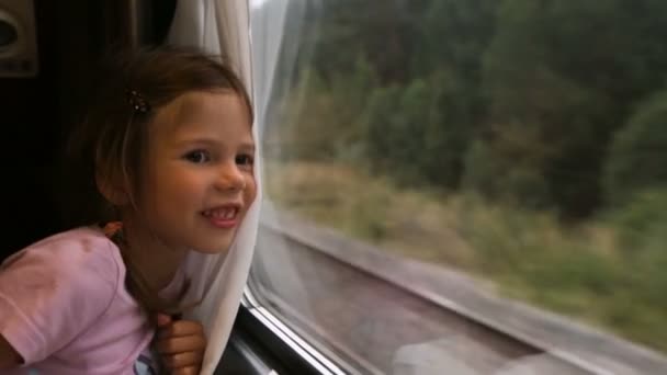 Pequeña niña mirando a través de la ventana del tren. — Vídeos de Stock