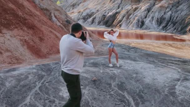 Photographe prenant des photos de belle femme sur un paysage vallonné de l'autre monde — Video