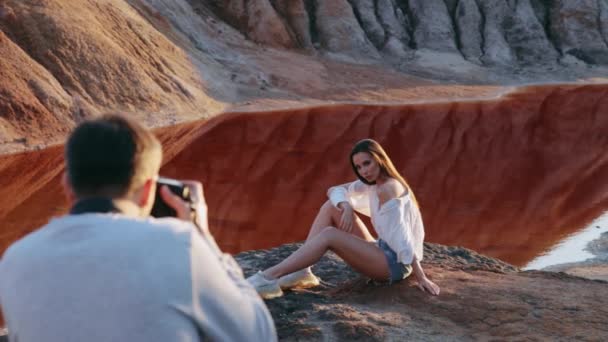 Photographe prenant des photos de belle femme sur un paysage vallonné de l'autre monde — Video