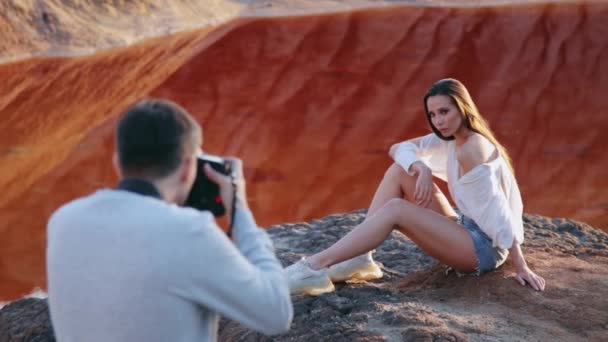 Fotografo che fotografa una bella donna su un paesaggio collinare ultraterreno — Video Stock