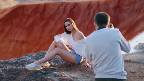 Fotograf robi zdjęcia pięknej kobiecie na nieziemskim pagórkowatym krajobrazie — Wideo stockowe