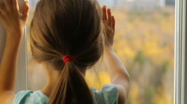 Sonbahar ormanında pencereden bakan küçük kız.