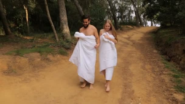 Joven hermosa pareja caminando a lo largo de la carretera rural en mantas — Vídeo de stock