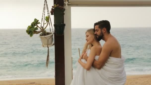 Молода красива пара на пляжі в ковдрах — стокове відео