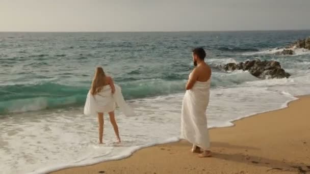 Молода красива пара на пляжі в ковдрах — стокове відео