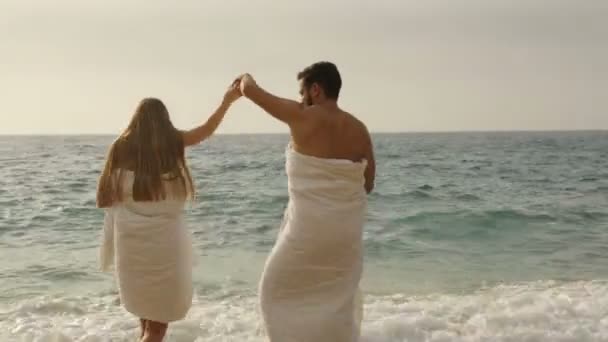 Jong mooi paar op het strand in dekens — Stockvideo