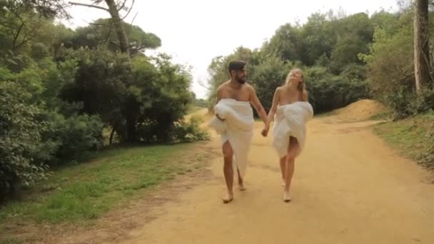 Kırsal yolda battaniyelerle yürüyen genç ve güzel bir çift. — Stok video