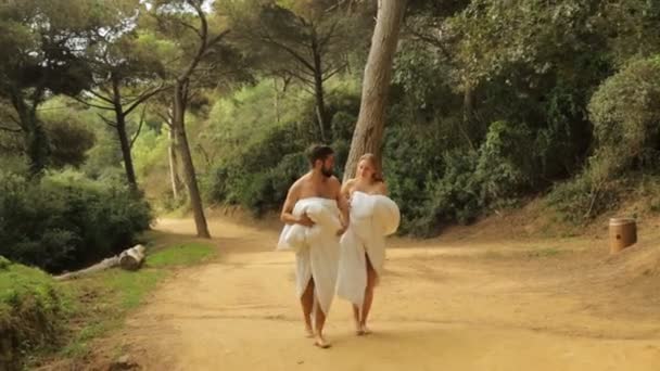 Jovem casal bonito andando ao longo da estrada rural em cobertores — Vídeo de Stock