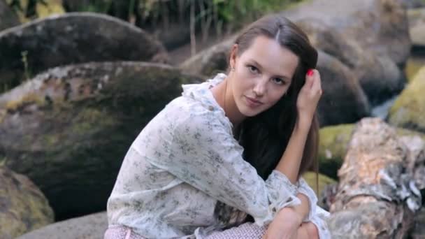 Gyönyörű lány ül a kövön az erdőben — Stock videók