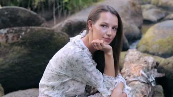 Piękna dziewczyna siedzi na kamieniu w lesie — Wideo stockowe