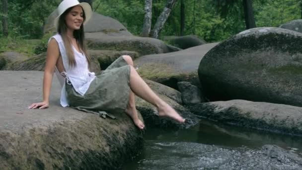 Bella ragazza seduta sulla pietra nella foresta e spruzzi d'acqua — Video Stock