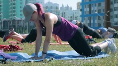 Bir grup kadın dışarıda şınav çekiyor.