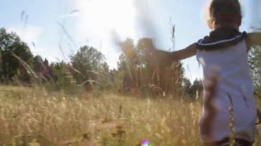 Küçük kız yaz tarlasında koşuyor.