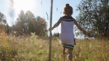 Küçük kız yaz tarlasında koşuyor.