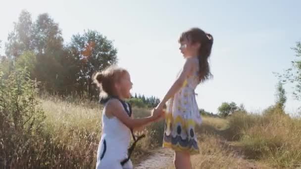 Дві маленькі дівчата стрибають по сільській дорозі — стокове відео