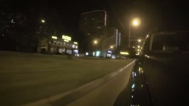 Şehrin bir yaz gecesi cadde boyunca araba taşır. Başlık üzerinden önden görünüm.