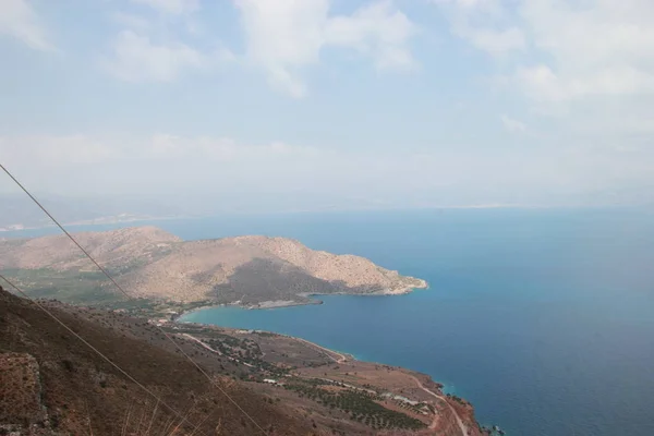 Een klein eiland in de zee met blauwe water voor de kust van Kreta — Stockfoto
