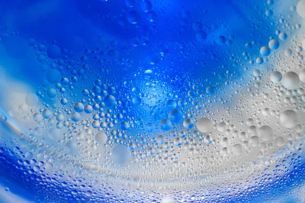 Blue ink flows inside fizzy liquid with bubbles creating round layers macro bright wallpaper
