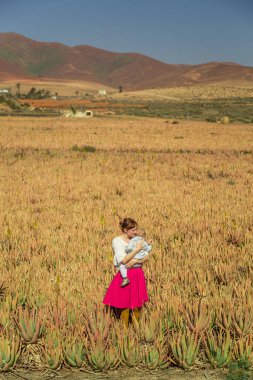 Aloe vera alan Fuerteventura, Kanarya Adaları, İspanya bebeği tutan genç kadın.