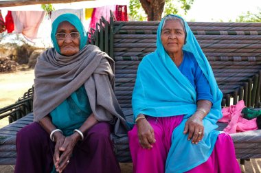 Hampi, Hindistan - 14 Şubat 2015: geleneksel giysiler ve baş eşarp yığılmış bankların üzerinde oturan giymiş iki yaşlı Hintli kadın.