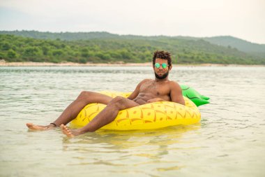 şişme ananas yatak şeklinde üzerinde yatan adam gülümseyen