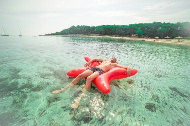 Yıldız şekilli şişme üzerinde yüzen adamın havadan görünümü.