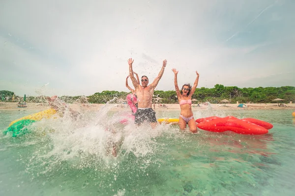 一群家人朋友在夏天的海滩上带着充气床垫疯狂地跑进大海 — 图库照片